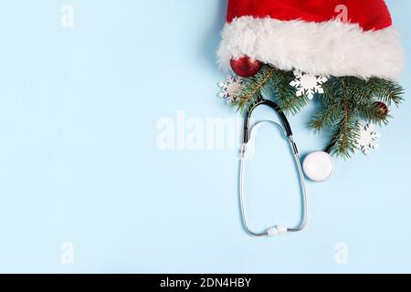 Medizinisches Stethoskop und weihnachtsdekorationen in Santa Claus rote Tasche auf blauem Hintergrund. Medizinische Winter Grußkarte. Kopierraum Stockfoto