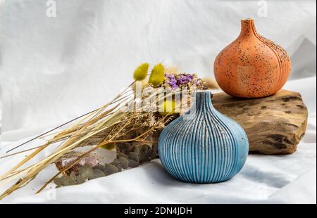 Zwei schöne kleine Keramikvasen mit Holzstämmen auf weißem Hintergrund. Keramik Geschirr, Wohnkultur. Stockfoto