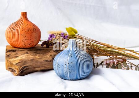 Zwei schöne kleine Keramikvasen mit Holzstämmen auf weißem Hintergrund. Keramik Geschirr, Wohnkultur. Stockfoto