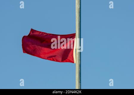 Rote Warnflagge flattert am Himmel Stockfoto