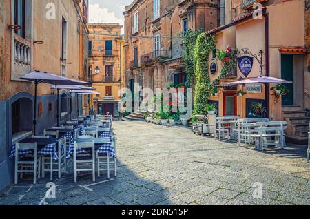 Tropea, Italien - 9. Mai 2018: Typisch italienische schmale Straße von Tropea Altstadt mit alten Gebäuden und Straßenrestaurant, Vibo Valentia, C Stockfoto