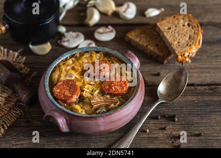 Weihnachts-Kohlsuppe in Keramikschale auf natürlichem Holzhintergrund. Stockfoto