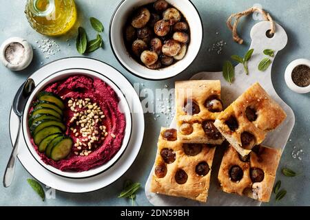 Rote Beete und Cashew Dip auf einem blauen Tisch mit karamellisierten Zwiebeln und veganem Mayo. Gesunder Snack oder Vorspeise und Focaccia Stockfoto