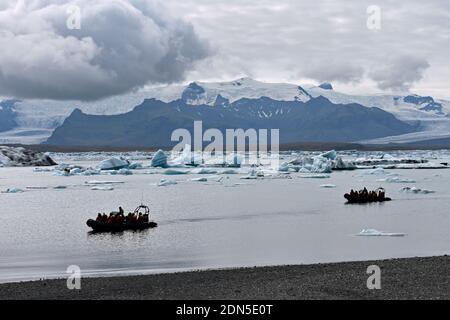 Zwei Tierkreisboote während einer Tour durch die Jokulsarlon Gletscherlagune in Südisland. Gletscher sind auf den Bergen zu sehen und Eisberge schweben auf dem See. Stockfoto