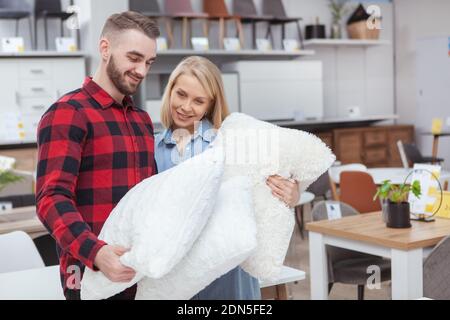 Schönes junges Paar Einkaufen für Bettwaren zusammen zu Hause Warenhaus, Kopierer Platz. Schöne Frau und ihr schöner Freund Untersuchung Kissen auf sa Stockfoto