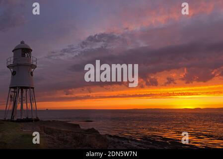 Ein Sonnenuntergangsbild mit dem Black Nore Lighthouse mit Blick auf den Bristol Channel an der Küste in der Nähe von Portishead, Somerset, England, Großbritannien. Stockfoto