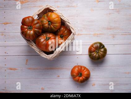 Große Tomaten im Korb auf einem Holzboden Stockfoto