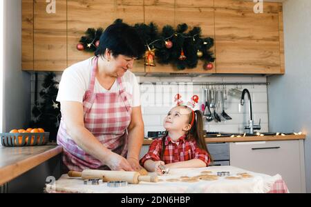 Oma und Enkelin schauen einander an, während sie in der Küche Kekse machen. Stockfoto