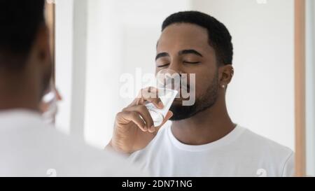 Junger Mann friedlicher afrikanischer Ethnie, der frisches Wasser trinkt. Stockfoto