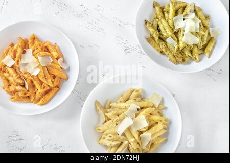 Portionen Penne-Pasta mit traditioneller, orangefarbener und gelber Pesto-Sauce Stockfoto