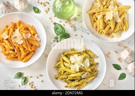 Portionen Penne-Pasta mit traditioneller, orangefarbener und gelber Pesto-Sauce Stockfoto