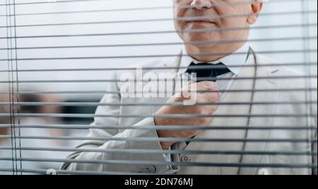 Nahaufnahme: Seriöser Business man steht vor dem Bürofenster Stockfoto