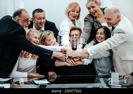 Nahaufnahme. Eine Gruppe von glücklichen Geschäftsleuten, die ihre Handflächen zusammenlegen. Stockfoto