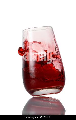 Rote Limonade spritzt ins Glas auf weißem Hintergrund Stockfoto