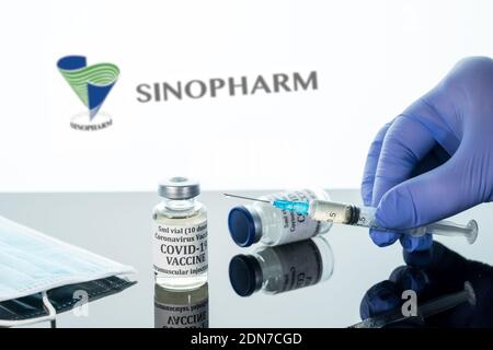 Morgantown, WV - 16. Dezember 2020: Kleine Flasche Coronavirus-Impfstoff mit Spritze mit Hintergrund des chinesischen Unternehmens Sinopharm Logo Stockfoto