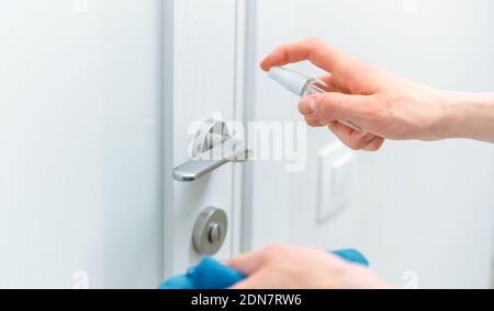 Nahaufnahme. Netter Mann sprüht antiseptisches Spray auf den Türgriff. Stockfoto