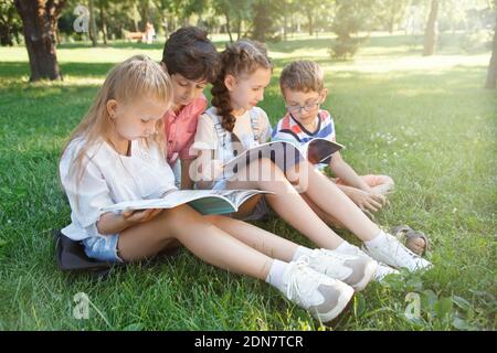SchuleKinder studieren im Freien auf dem Rasen im öffentlichen Park Stockfoto