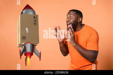 Erstaunt und schockiert Ausdruck eines Jungen, der ein Paket erhält. Oranger Hintergrund Stockfoto