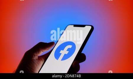 The Facebook logo is seen on an iPhone in this photo illustration in Warsaw, Poland on December 17, 2020. Facebook has disabled several features on it Stockfoto