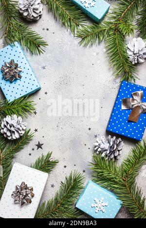Weihnachten oder Winter Komposition. Weihnachtsgeschenke, Tannenzweige und Ornamente auf grauem Steingrund. Flach liegend, Draufsicht, Kopierbereich. Stockfoto