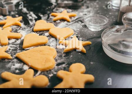 Foto von einigen ungekockten Lebkuchenfiguren auf einem schwarzen Tisch Mit etwas Mehl Stockfoto