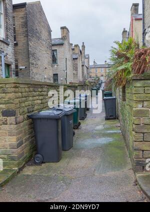 Mülltonnen in einer Gasse zwischen Reihenhäusern in Saltaire, Yorkshire, England. Stockfoto