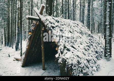 Primitive bushcraft Überleben Schutz mit Weihnachten Girlande Glühbirnen im Winter Wald Stockfoto