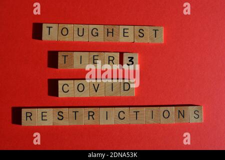 Härteste Stufe 3 Covid Einschränkungen, Wörter in Holzbuchstaben isoliert auf rotem Hintergrund Stockfoto