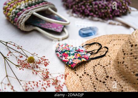 Womans stilvolle, bunte, Gesichtsmaske mit wesentlichen Coronavirus Covid-19 Sommer Urlaub Reise Artikel Stockfoto