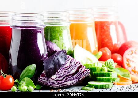 Bunte vegane Gemüsesäfte und Smoothies in Glasflaschen auf grauem Tisch, selektiver Fokus Stockfoto