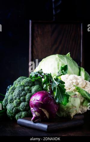 Verschiedene Arten von Kohl wie Weißkohl, Blumenkohl, Brokkoli, Kohlrabi auf dunklem Tisch, Herbsternte, selektiver Fokus Stockfoto