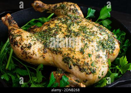 Chimichurri Brathähnchen: Ein ganzes Huhn in einer gusseisernen Pfanne mit Chimichurri-Sauce gebraten Stockfoto