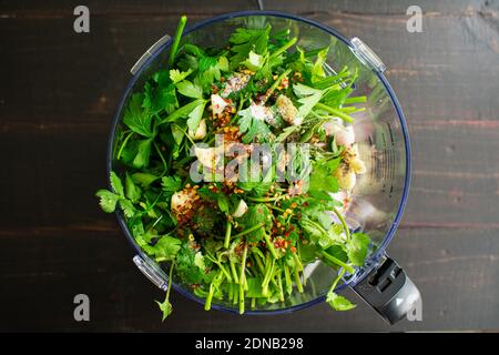 Chimichurri Zutaten in einer Küchenmaschine: Petersilie, Koriander, Knoblauch und andere Chimichurri-Zutaten in einer Schüssel für die Küchenmaschine Stockfoto