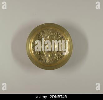 Dish, Brass, Deep round dish with narrow shallow rim; bottom decorated with repoussé design. About a small raised central boss surrounded by a band of illegible lettering, five onion-shaped petals spring outward, separating five lion masks facing outward from whose mouth spring three stems, the central stem terminating in a bunch of conventionalized grapes, the flanking ones terminating in a grape leaf and volute., Germany, ca. 1500, metalwork, Decorative Arts, Dish Stockfoto