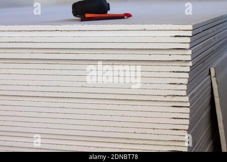 A stack of drywall sheets with a tape measure, pen and pencil lying on top, copy space Stock Photo