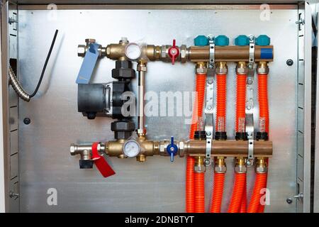 Verteiler und Pumpengruppe für Fußbodenheizung mit Servomotor und Durchflussmesserventilen, in einem Privathaus installiert Stockfoto