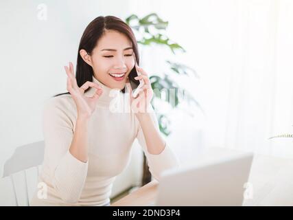 young woman working on  laptop and talking on the phone in the home office Stock Photo