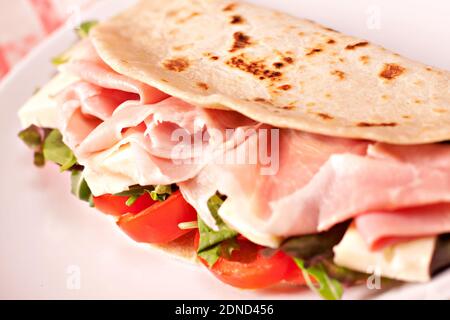 Traditionelle italienische Piadina mit Schinken, Käse, Tomaten und Salat. Stockfoto