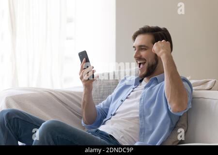 Emotional young caucasian man celebrating mobile win. Stockfoto
