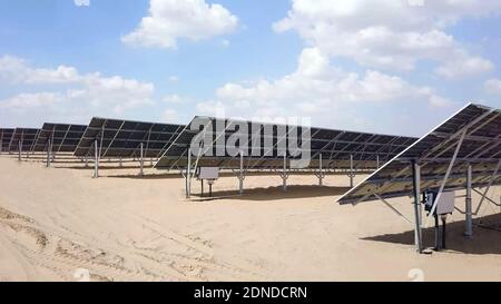 Nahaufnahme von Solarmodulen in der Wüste mit Blick auf die Verteilertafel mit bewölktem Himmel im Hintergrund. Photovoltaik-PV-Module in einem Solarenergieplan Stockfoto