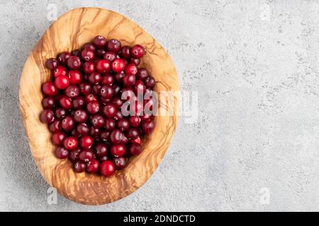 Reife frische Preiselbeeren in einer Holzschüssel auf einem grauen Tisch, Kopierraum, Draufsicht, flaches Lay Stockfoto