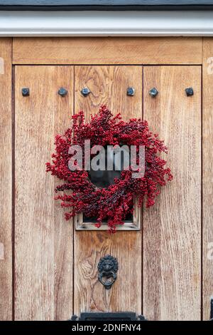 Red berry christmas wreath on a town house wooden door. Woodstock, Oxfordshire, England Stock Photo