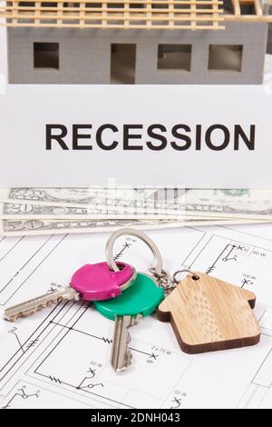 Keys of home, currencies dollar and inscription recession on housing plan. Concept of real estate crisis caused by coronavirus. Small house under cons Stockfoto