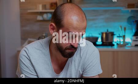 Gestresster Mann arbeitet Überstunden fühlt Augenermüdung nach Computer-Arbeit spät in der Nacht. Porträt eines stark beschäftigten, fokussierten Mitarbeiters, der moderne drahtlose Technologie verwendet und Überstunden für das Lesen von Schreibarbeiten macht Stockfoto