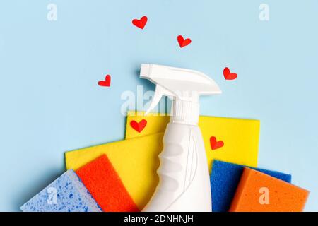 Buntes Reinigungsset für verschiedene Oberflächen in Küche, Bad und anderen Räumen mit roten Herzen auf blauem Hintergrund. Reinigungsdienstkonzept. Früh Stockfoto