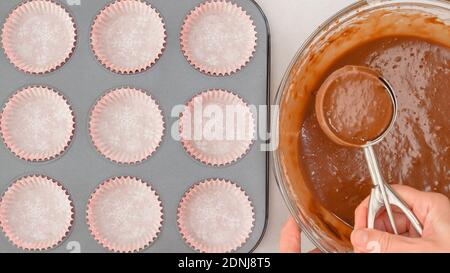 Schokoladenmuffins Rezept. Schokoteig mit einer Eislöffel in eine ausgekleidete Cupcake-Pfanne gießen. Nahaufnahme, flach liegend Stockfoto