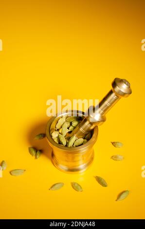 Indischer Messingmörtel und Stößel Set mit grünen Kardamom-Hülsen in Mörtel. Obere Winkelansicht. Studioaufnahme Stockfoto