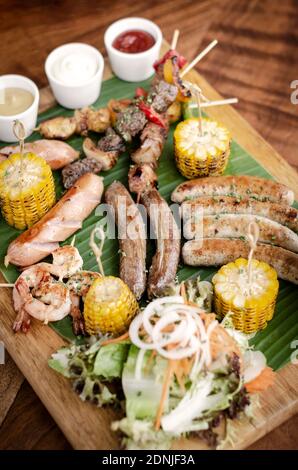 Bio gemischte Grill Grillplatte rustikales Menü mit Würstchen, Spieße, Beilagen und Saucen Stockfoto