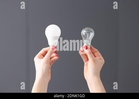 Frau mit zwei verschiedenen Glühbirnen in den Händen Nahaufnahme Stockfoto