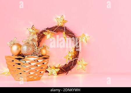 Weihnachtliche festliche Hintergrund mit goldenem Funkeln Dekoration, weihnachtskranz, glühende Girlande auf rosa Hintergrund. Stockfoto